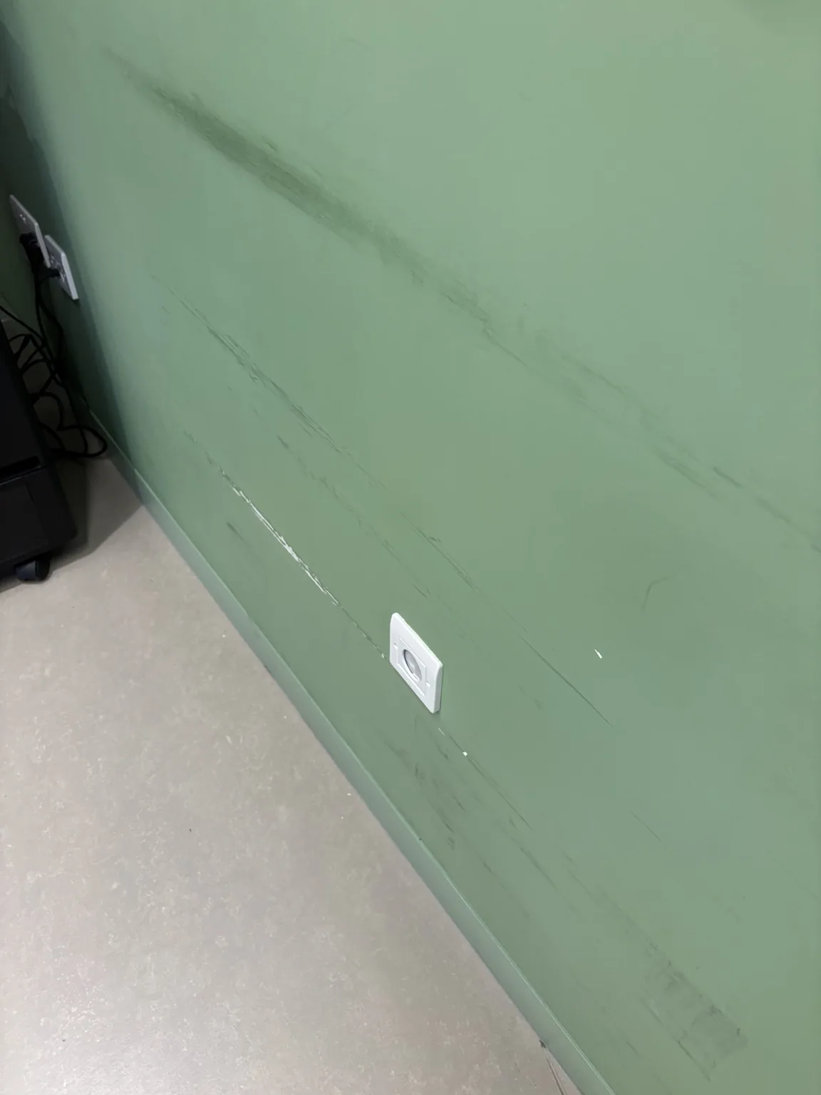 Scuffed green commercial interior wall before remedial painting in East London