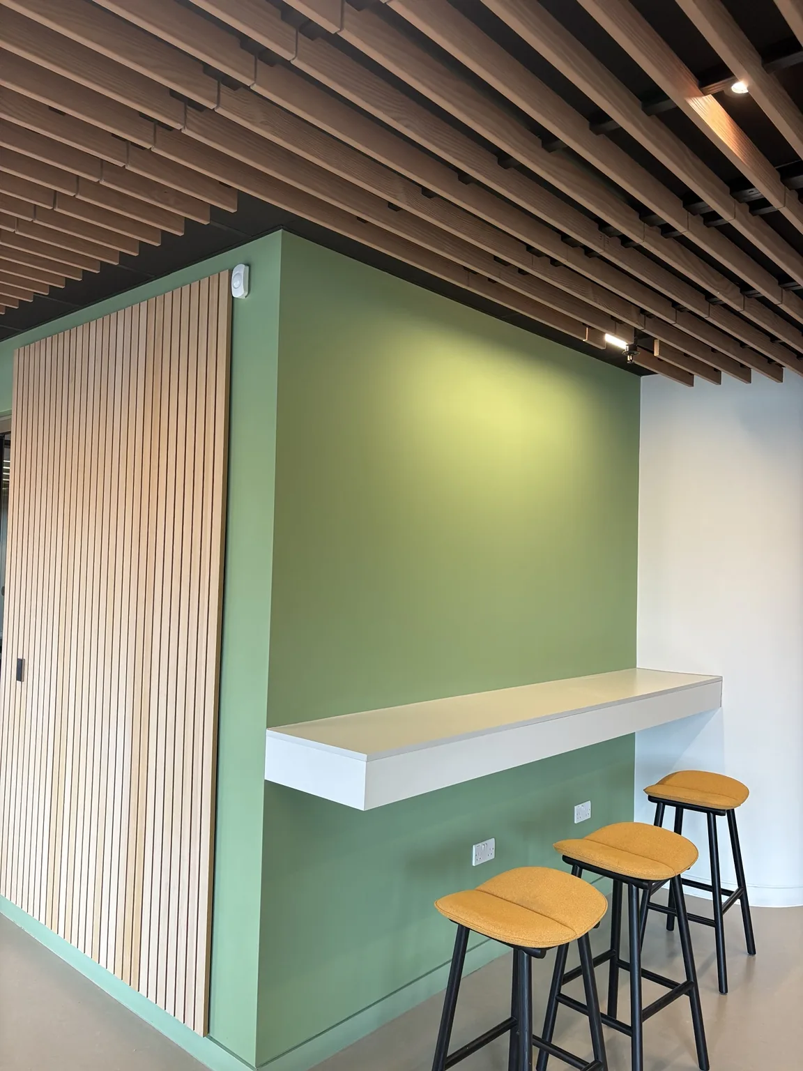 Completed green feature wall and commercial breakout area after painting in East London